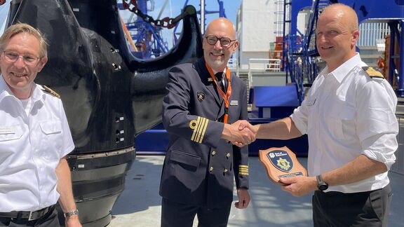 Ruud Hoogesteger, operationeel manager bij de Divisie Havenmeester, overhandigt het traditionele Rotterdamse havenschildje aan de bemanning van het schip.