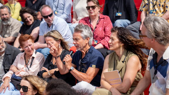 Genodigden luisterden bij de opening naar een voordracht van schrijver Dirk van Weelden en een vraaggesprek met Mira Matić, Jamie van Lede en fotograaf Carel van Hees (hier met de microfoon in zijn hand). Foto: Marc Nolte