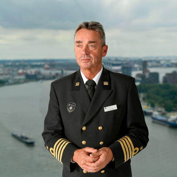 Persoon in formeel uniform met een rivier en stadszicht op de achtergrond
