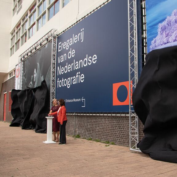 Vivienne de Leeuw, CFO van Havenbedrijf Rotterdam, en Birgit Donker, directeur van het Nederlands Fotomuseum, onthulden maandag 26 augustus een nieuw geveldoek.