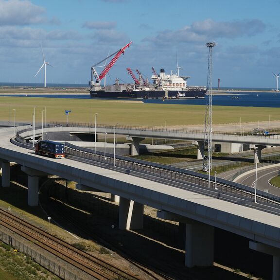 Lkw-Fahrten entlang der Container Exchange Route mit der Pioneering Spirit im Hintergrund