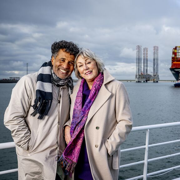 Mensen maken een selfie op de rondvaartboot van Portlantis met een groot containerschip op de achtergrond