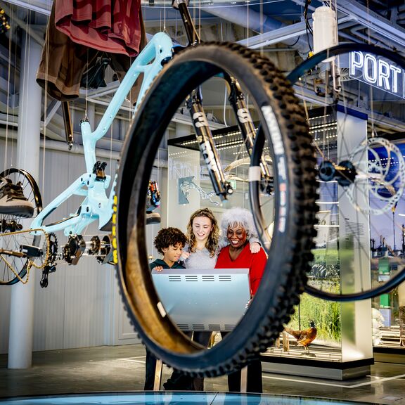 Gezin kijkt bij een display met een fiets in Portlantis