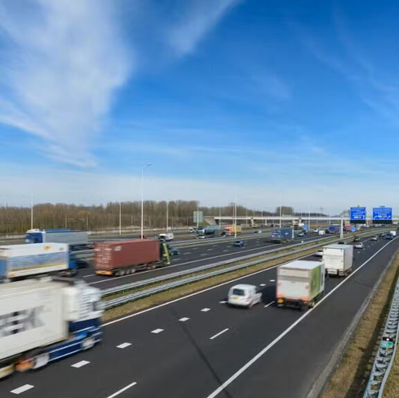 Snelweg tussen Maasvlakte en Vaanplein met rijdend vrachtverkeer onder een blauwe lucht.