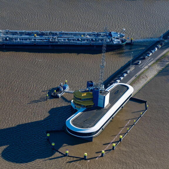 „Luftaufnahme eines Frachtschiffs neben einer industriellen Plattform im Hafen.“